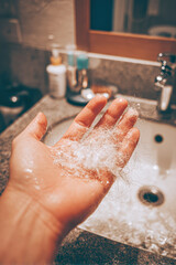 Fototapeta premium A hand holds a handful of wet hair strands above a sink, showcasing a moment of personal grooming in a bathroom environment.