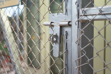 Close-up at metal door bolt on the fence wire gate, it using to secure the gate during it closed. Building equipment object, selective focus.