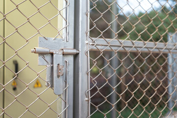 Close-up at metal door bolt on the fence wire gate, it using to secure the gate during it closed. Building equipment object, selective focus.