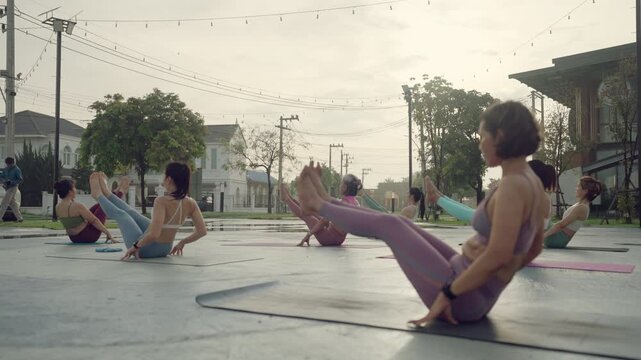 Active women holding a deep bound squat pose during early morning yoga class, focusing on breath and hip opening.