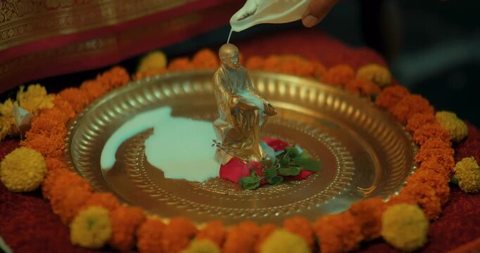 Devotees performing Sai Baba&rsquo;s puja with a small brass idol, lighting lamps, and offering fresh flowers, creating a serene and devotional atmosphere filled with faith and positive energy