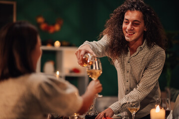 Man pouring white wine for woman during romantic dinner date
