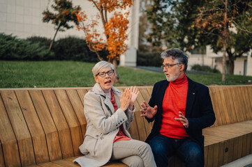 Senior couple arguing and gesturing on park bench