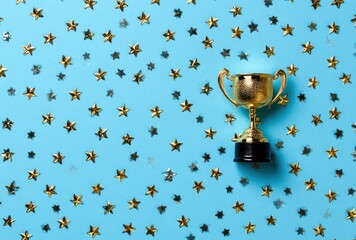 Golden trophy atop black base surrounded by numerous small gold stars, scattered across a vibrant baby blue background. Celebratory and festive