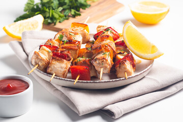 Delicious grilled chicken skewers with capsicum, lemon, salad and ketchup on a plate over the...