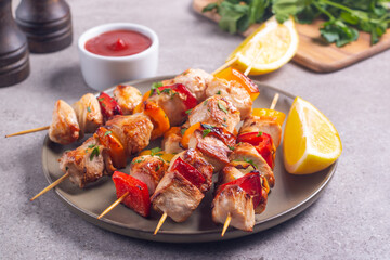 Delicious grilled chicken skewers with capsicum, lemon, salad and ketchup on a plate over the table. Chicken kebab. Healthy food concept.