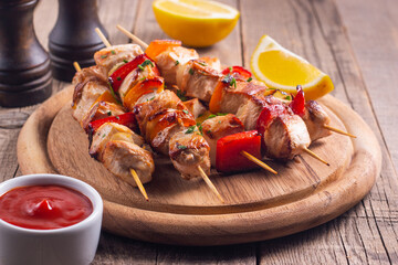 Delicious grilled chicken skewers with capsicum, lemon, salad and ketchup on a plate over the table. Chicken kebab. Healthy food concept.