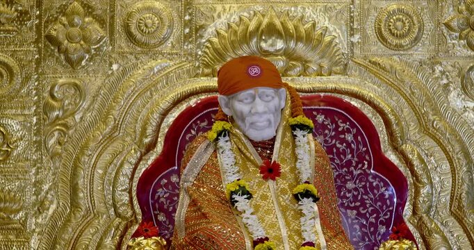 Sai Baba is seated peacefully in the temple, radiating a divine positive aura that fills the atmosphere with serenity and devotion