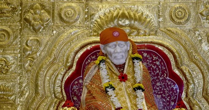 Sai Baba is seated peacefully in the temple, radiating a divine positive aura that fills the atmosphere with serenity and devotion