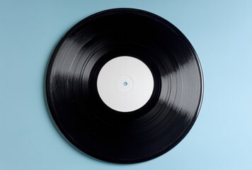 Fototapeta premium A classic black vinyl record with a blank white label is centered against a simple, solid light blue background, creating a clean, minimalist composition