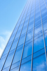 Obraz premium Modern glass skyscraper reflecting clear blue sky and clouds