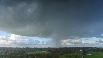 Breathtaking balcony view overlooking the lush green fields of Holland's countryside during a stormy summer sunset near Amsterdam, Netherlands
