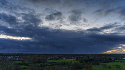 Breathtaking balcony view overlooking the lush green fields of Holland's countryside during a stormy summer sunset near Amsterdam, Netherlands