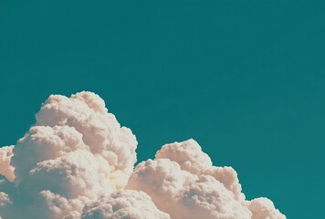 Cumulus clouds burst from below in this image, against a saturated teal sky, evoking feelings of calm and freedom