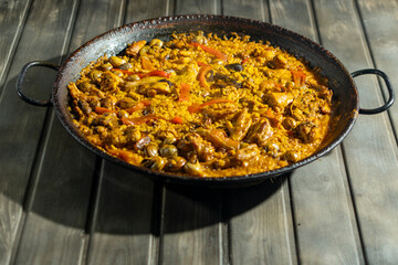 A large paella with lots of meat, rice, and vegetables.