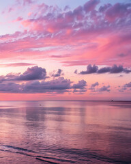 Fototapeta premium Serene ocean horizon at sunset with vibrant pink and purple clouds reflecting on the calm water creating a peaceful and beautiful natural landscape