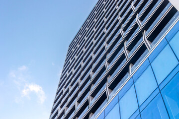 Modern high-rise building with unique geometric facade against a clear blue sky