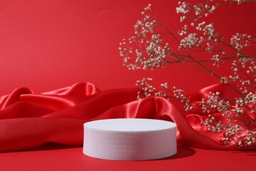 Promotion. Podium for product presentation, fabric and gypsophila flowers on red background