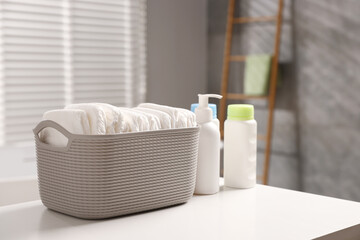 Baby bathing products and diapers on white table in bathroom