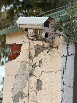 Security camera mounted on cracked building wall showing urban decay and infrastructure