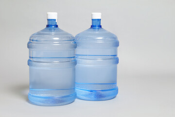 Cooler bottles with water on light grey background, closeup. Space for text