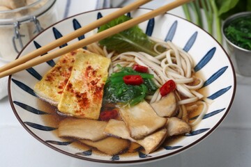 Tasty ramen with king oyster (eryngii) mushrooms in bowl on light table, closeup