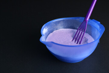 Blonde hair care cosmetic product. Powder in bowl and spatula on black background, closeup. Space for text