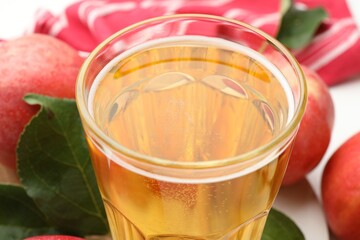 Fresh cider in glass and apples on table, closeup