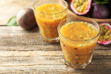 Tasty passion fruit drink and fresh fruits on wooden table, closeup. Space for text