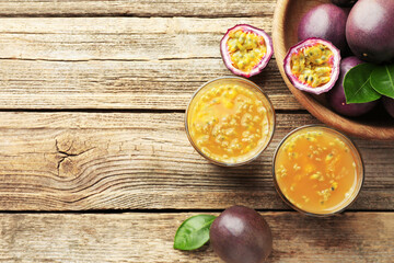 Tasty passion fruit drink and fresh fruits on wooden table, flat lay. Space for text