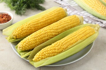 Tasty boiled corncobs on light table, closeup