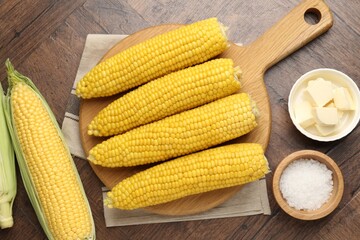 Tasty boiled corncobs, salt and butter on wooden table, flat lay
