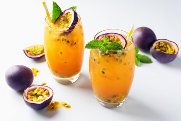 Tasty passion fruit drink with mint in glasses and fresh fruits on white table