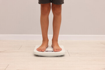 Little boy standing on scales indoors, closeup
