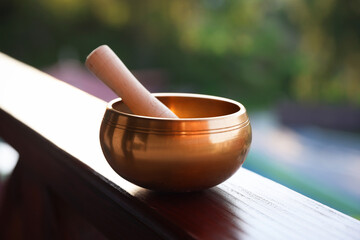 Tibetan singing bowl with mallet on handrail outdoors, closeup