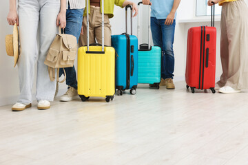 People with luggages waiting in queue indoors, closeup