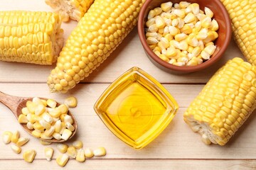 Corn oil, kernels and cobs on white wooden table, flat lay