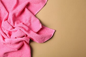 Pink terry towel on beige background, top view. Space for text