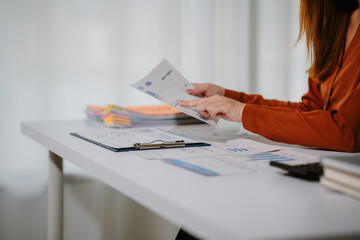 Young beautiful asian businesswoman holding unofficial spreadsheet paper accounting documents...