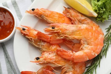 Tasty grilled shrimps served with lemon, lettuce, rosemary and sauce on table, flat lay. Delicious seafood dish