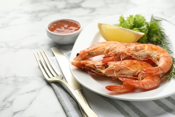 Tasty grilled shrimps served with lemon, lettuce, rosemary and sauce on white marble table, closeup. Delicious seafood dish
