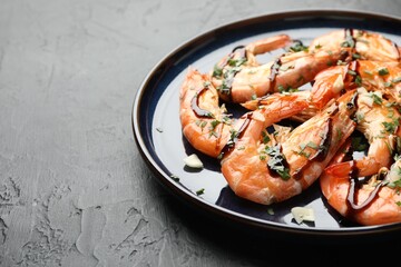 Delicious seafood dish. Tasty grilled shrimps with sauce on black table, closeup. Space for text