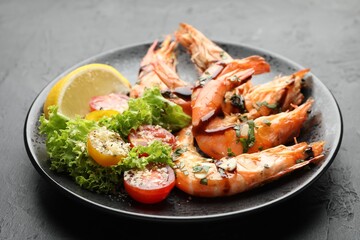 Tasty grilled shrimps served with salad and lemon on black table, closeup. Delicious seafood dish