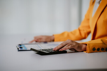 Young beautiful asian businesswoman holding unofficial spreadsheet paper accounting documents...
