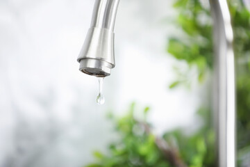 Save water concept. Water dripping from tap indoors, closeup. Space for text