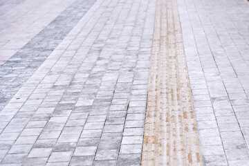 Paving slabs and tactile tiles for blind pedestrians fully covered in salt crystals during harsh winter treatment with excess salt creating environmental concerns and urban walkway damage