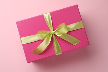 Beautiful gift box with bow on pink background, top view