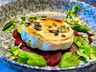 Soft moist Camembert cheese on top of a green salad