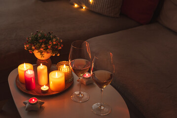 Cozy evening scene with candles, wine glasses and warm lighting.