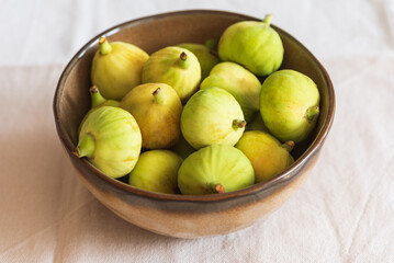 Fresh Green Figs in Ceramic Bowl on Light Fabric Background